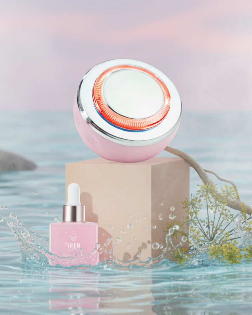 The SKIN GENIE PRO Hydration Set by Fast Bundle, featuring a pink dropper bottle and facial cleansing device, rests on a beige block amid water, a branch, and light mist beneath a pastel sky.