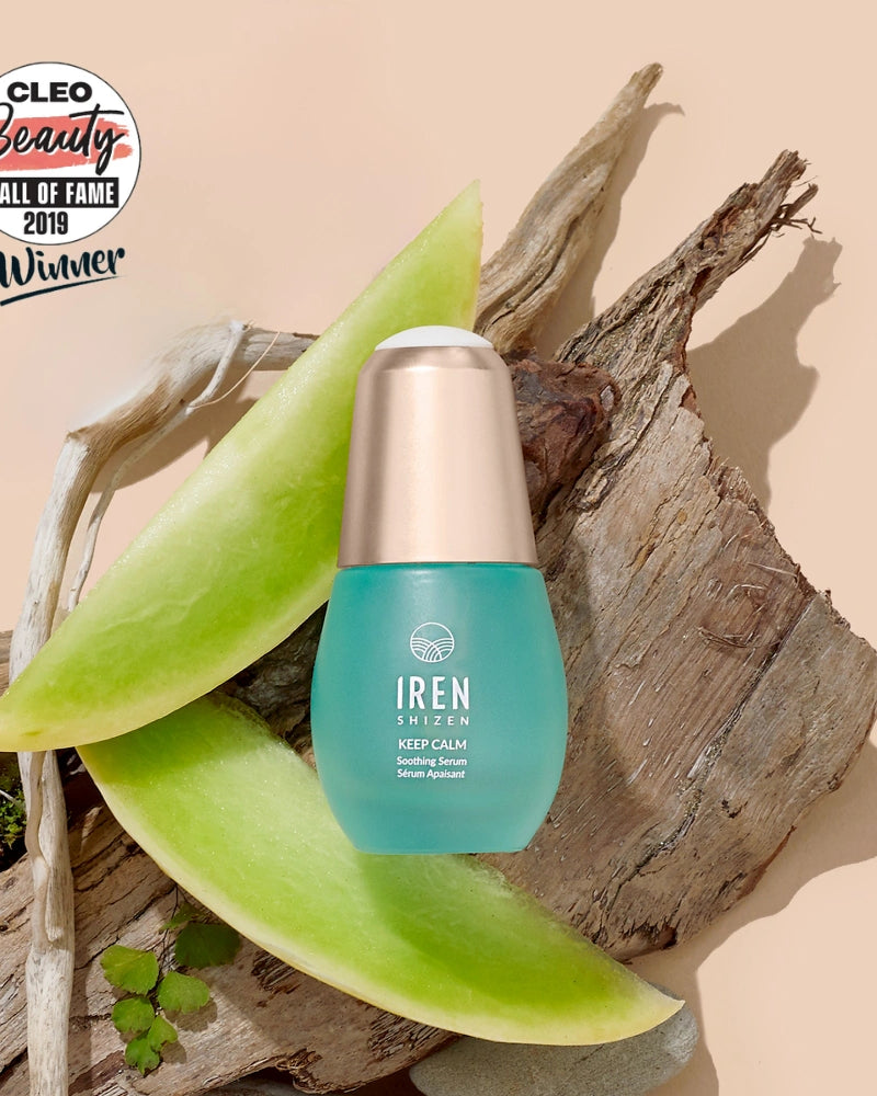 A bottle of IREN Shizen KEEP CALM Soothing Serum rests on wood with aloe vera slices, next to a Cleo Beauty Hall of Fame 2019 Winner badge—ideal for sensitive skin, eczema, and rosacea care.