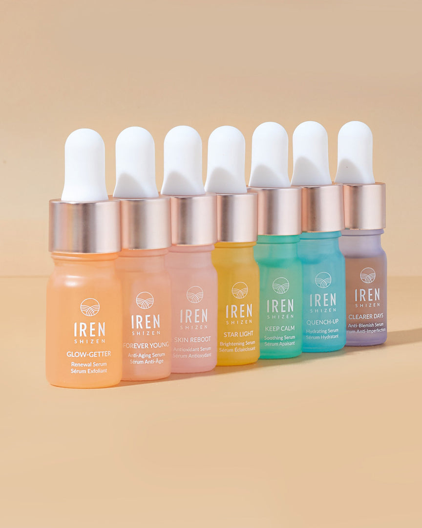 A set of Japanese skincare CLEAR UP Anti-Blemish Discovery Kits by IREN Shizen featuring different colored liquids on a beige background.