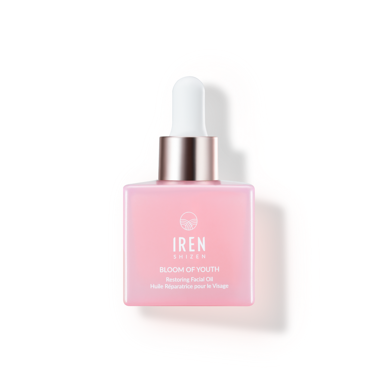 Un flacon rose léger d'huile visage régénérante BLOOM OF YOUTH avec compte-gouttes, présenté sur un fond assorti à un échantillon de produit IREN Shizen.