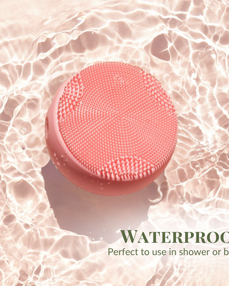 The pink SKIN GENIE PRO Cleansing Brush + LED Light Therapy by IREN Shizen floats on water, with text in the bottom right corner: "Waterproof, perfect to use in shower or bath. #show-lang-en