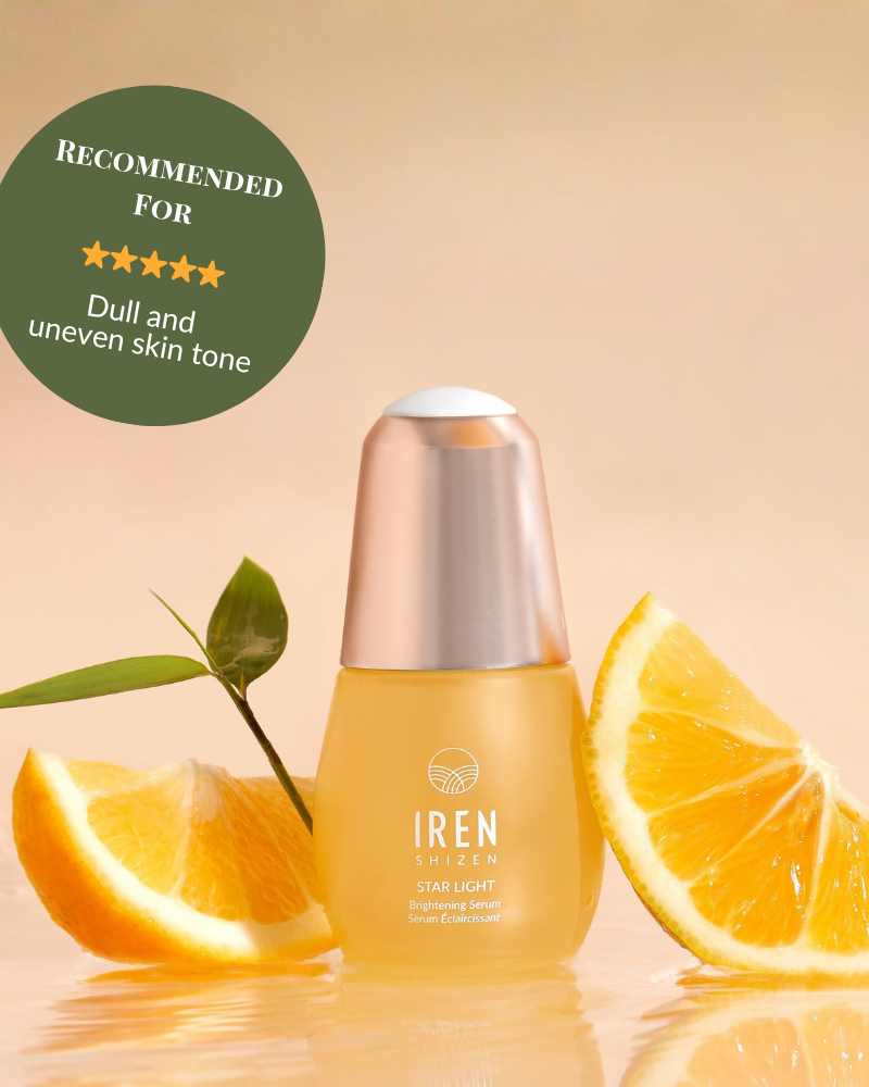A bottle of IREN Shizen STAR LIGHT Brightening Serum is shown with orange slices and a green leaf. The label suggests it for dull, uneven skin tone and dark spots to promote a naturally radiant complexion. #show-lang-en