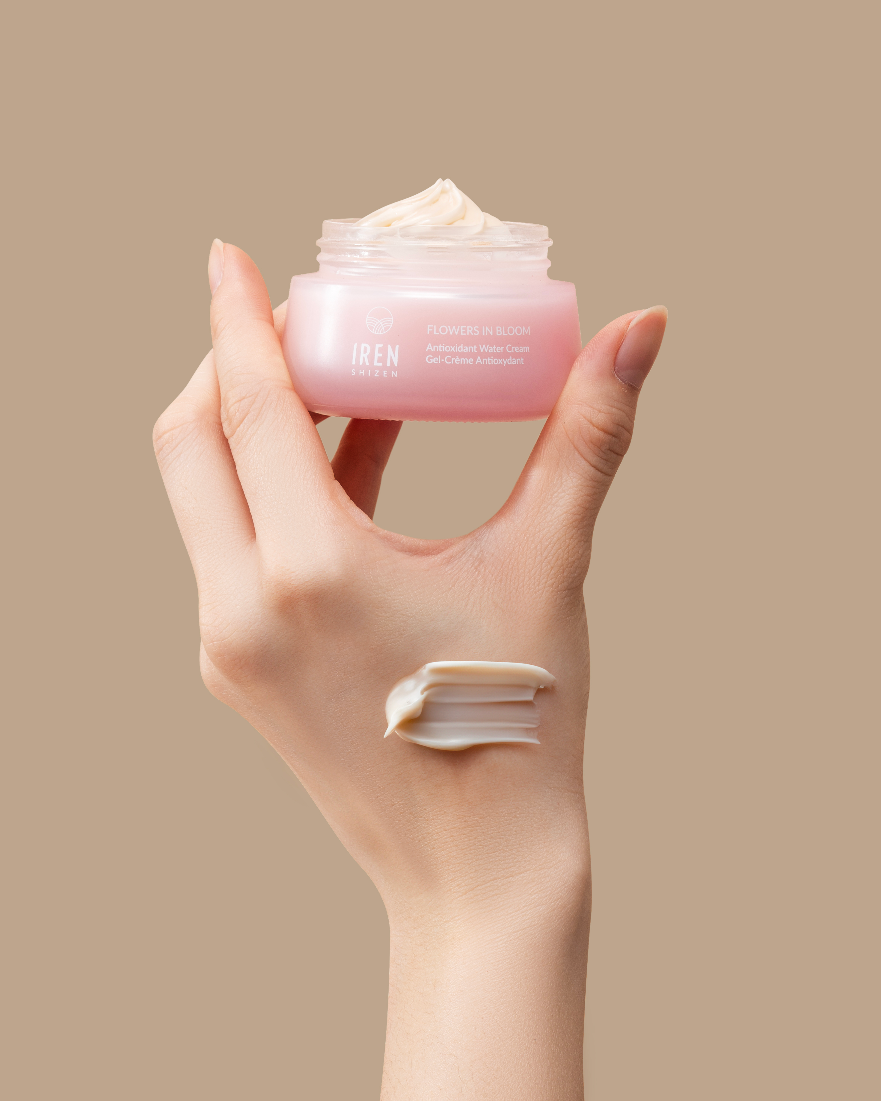 A hand holding a jar of FLOWERS IN BLOOM Antioxidant Water Cream by IREN Shizen. all-groups