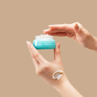 A person holding a jar of FREEZE THE YOUTH Hydra Firming Cream from IREN Shizen. #all-groups