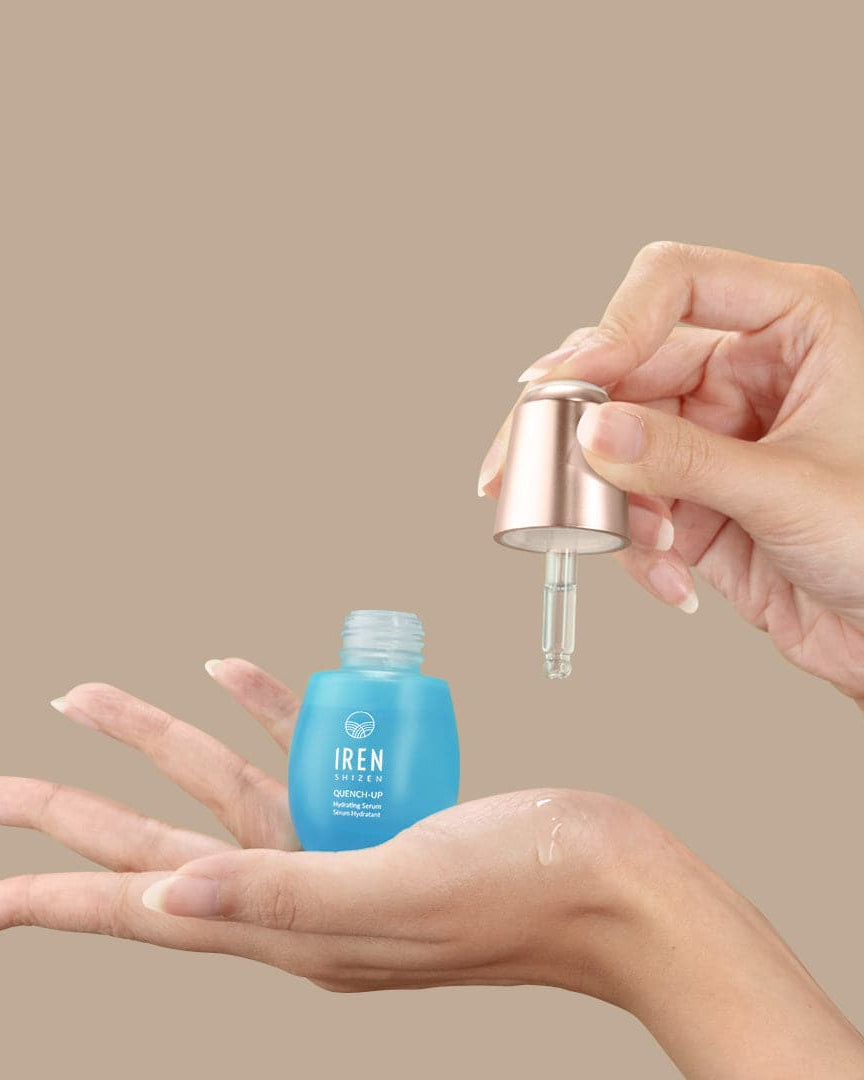 A woman's hand holding a bottle of custom Japanese skincare, the QUENCH-UP Hydrating Serum by IREN Shizen. #all-groups