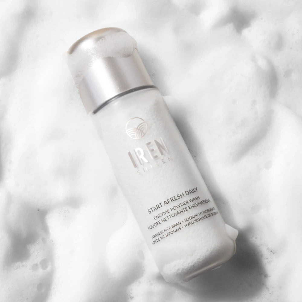 A bottle of IREN Shizen START AFRESH DAILY Enzyme Powder Wash, a gentle daily exfoliant, is seen from above surrounded by white foam.