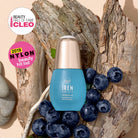 A blue bottle of IREN Shizen QUENCH-UP Hydrating Serum with hyaluronic acid is displayed on tree bark with blueberries, next to CLEO and NYLON beauty award badges.