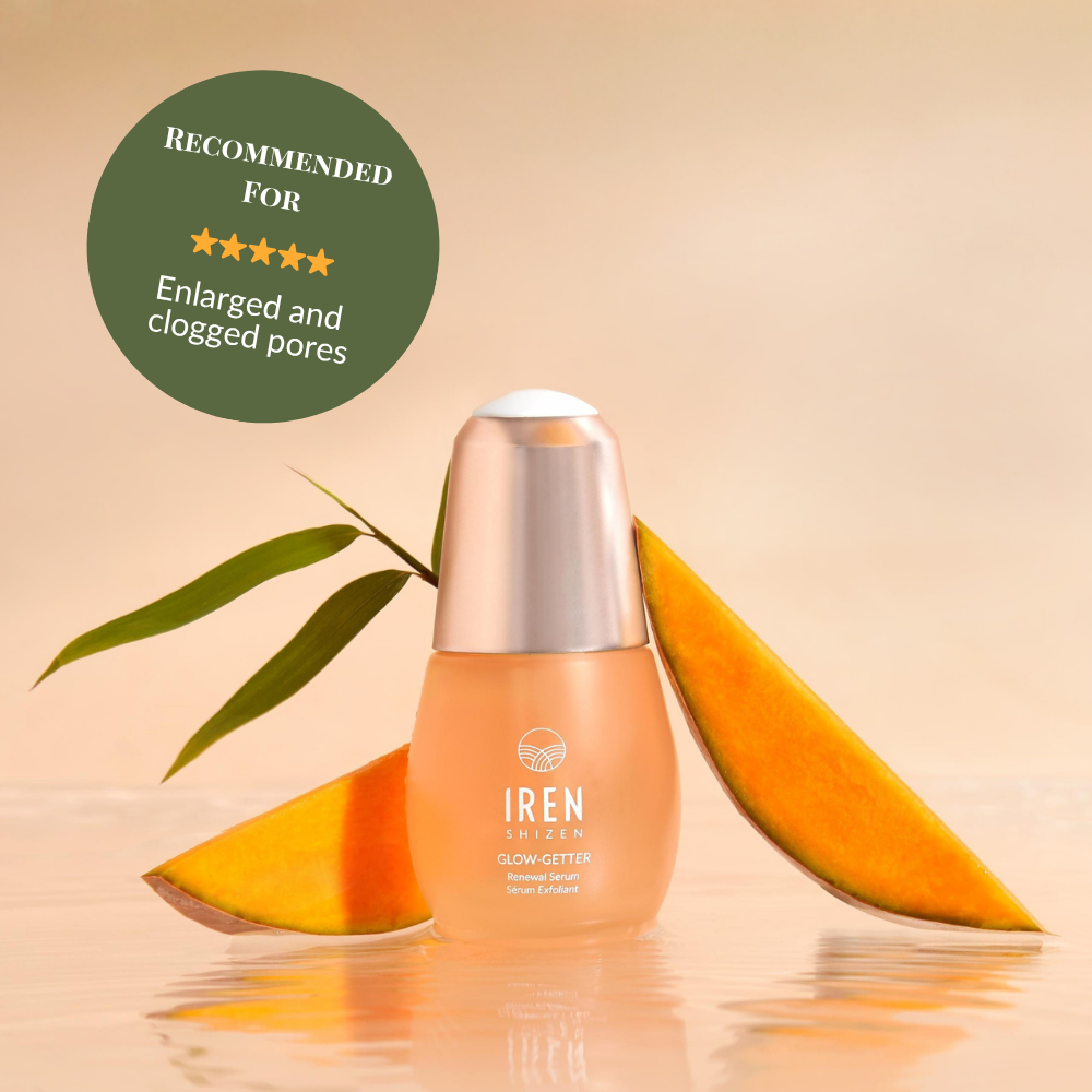 A bottle of IRÉN Shizen GLOW-GETTER Renewal Serum is shown with mango slices and a leaf, with a label recommending it to exfoliate and reduce blackheads for enlarged or clogged pores.