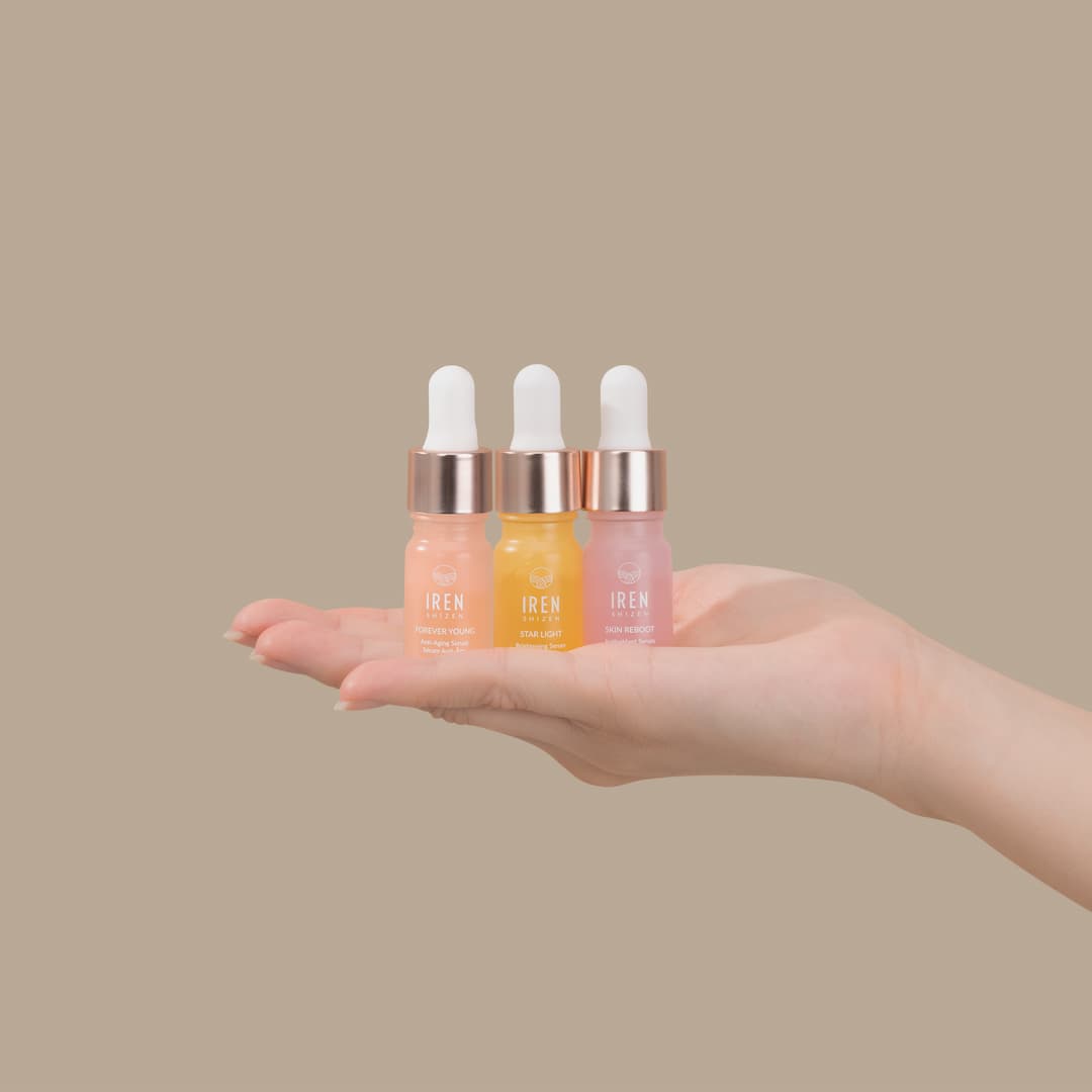 A person's hand holding the GLOW UP Anti-Aging Discovery Kit by IREN Shizen, consisting of serum minis.