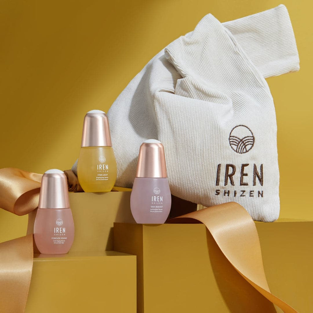 A custom Japanese skincare set by IREN Shizen GLOW UP, featuring onsen skincare products in three bottles and a bag, displayed against a vibrant yellow background.