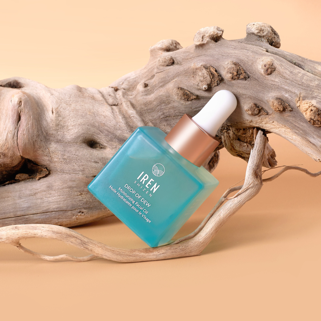 A bottle of IREN Shizen's MICROBIOME REPAIR Pre and Postbiotic Facial Oils sitting on a piece of driftwood.