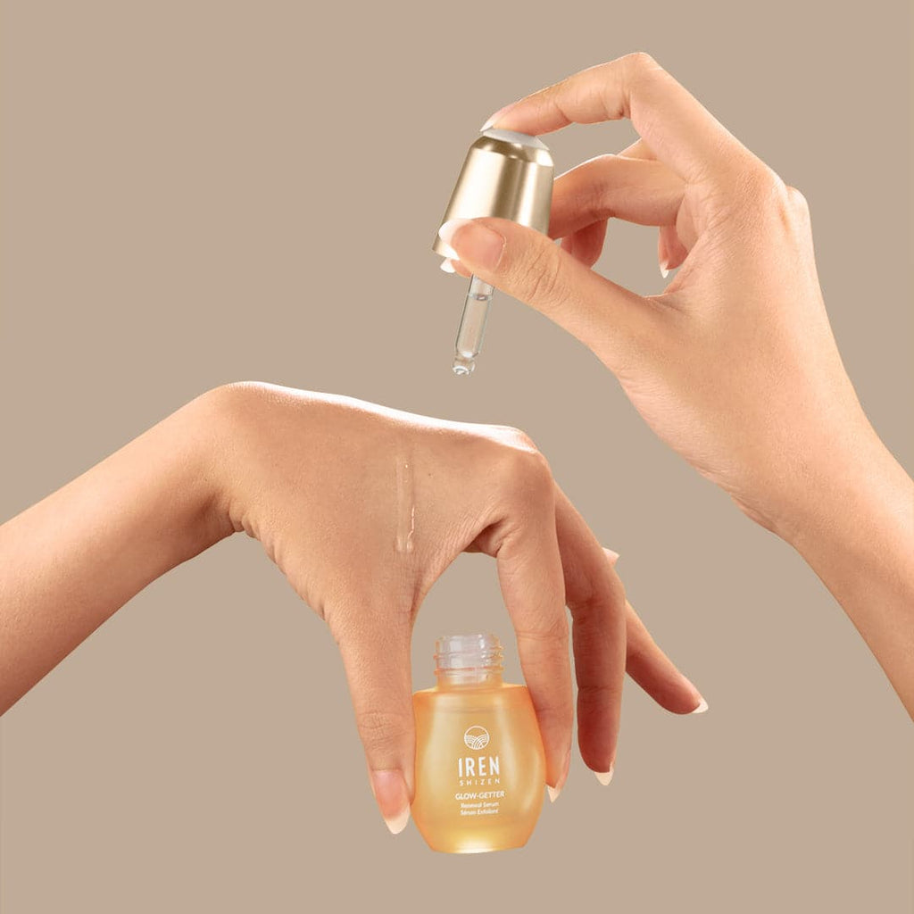 A woman's hand is holding a bottle of IREN Shizen's customized GLOW-GETTER Renewal Serum.