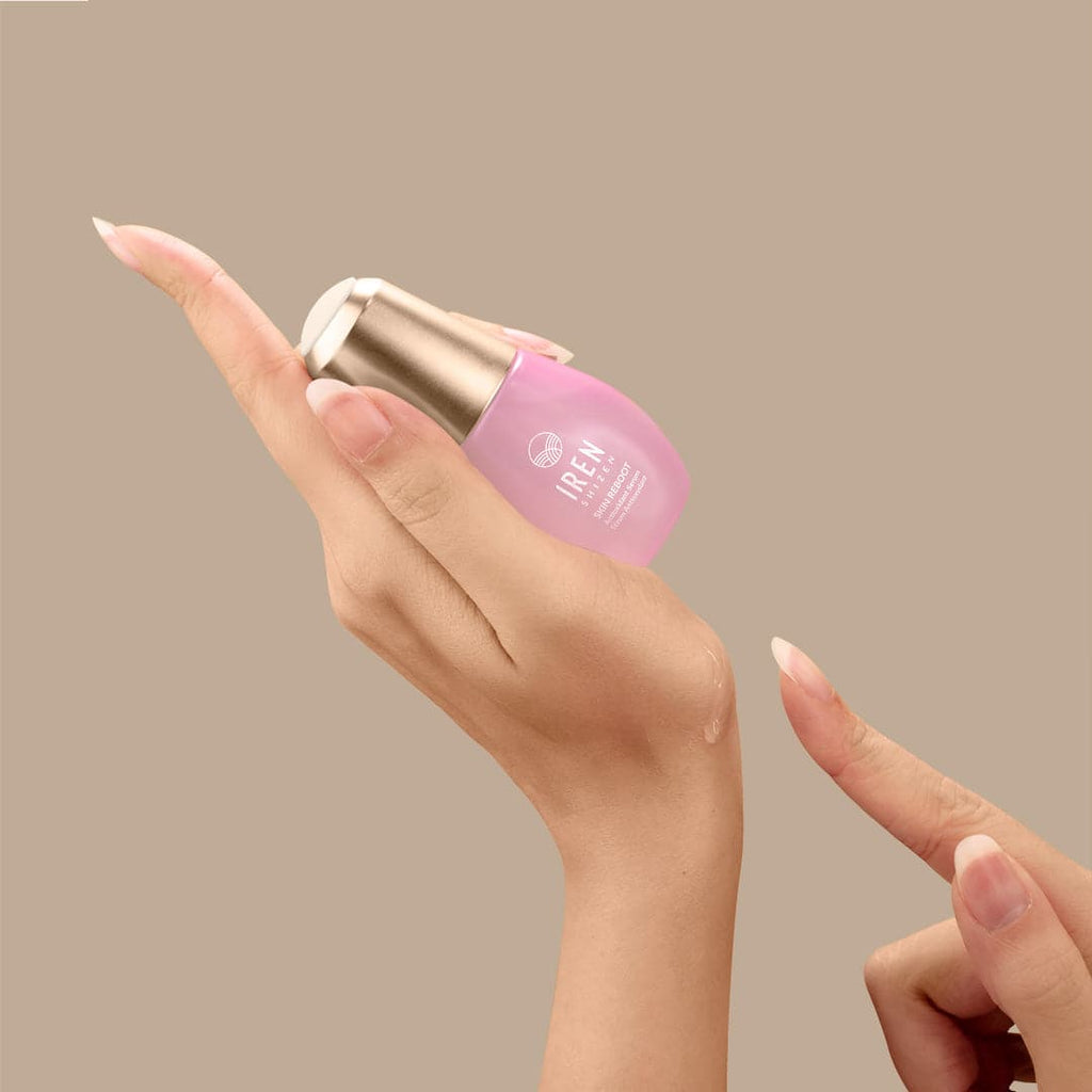 A woman's hand holding a bottle of customized Japanese skincare serum by IREN Shizen.