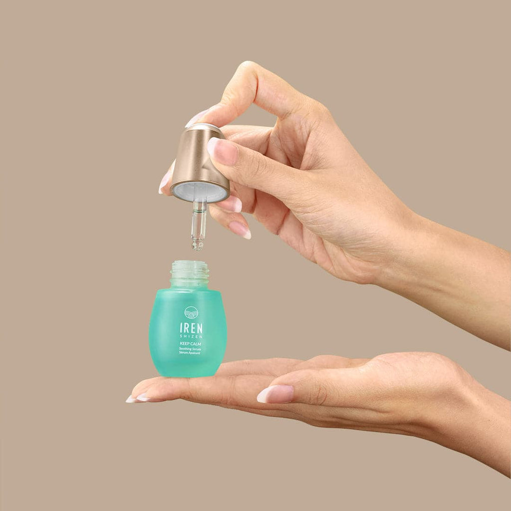 A woman's hand holding a bottle of IREN Shizen's KEEP CALM Soothing Serum, an onsen-based Japanese skincare product.