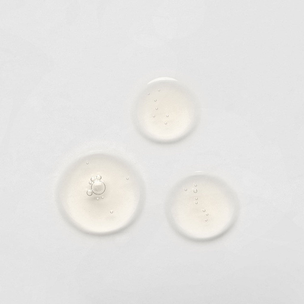 Three drops of customized skincare from IREN Shizen's onsen skincare range, the AGE DEFENSE Pro-Collagen Set, on a white surface.