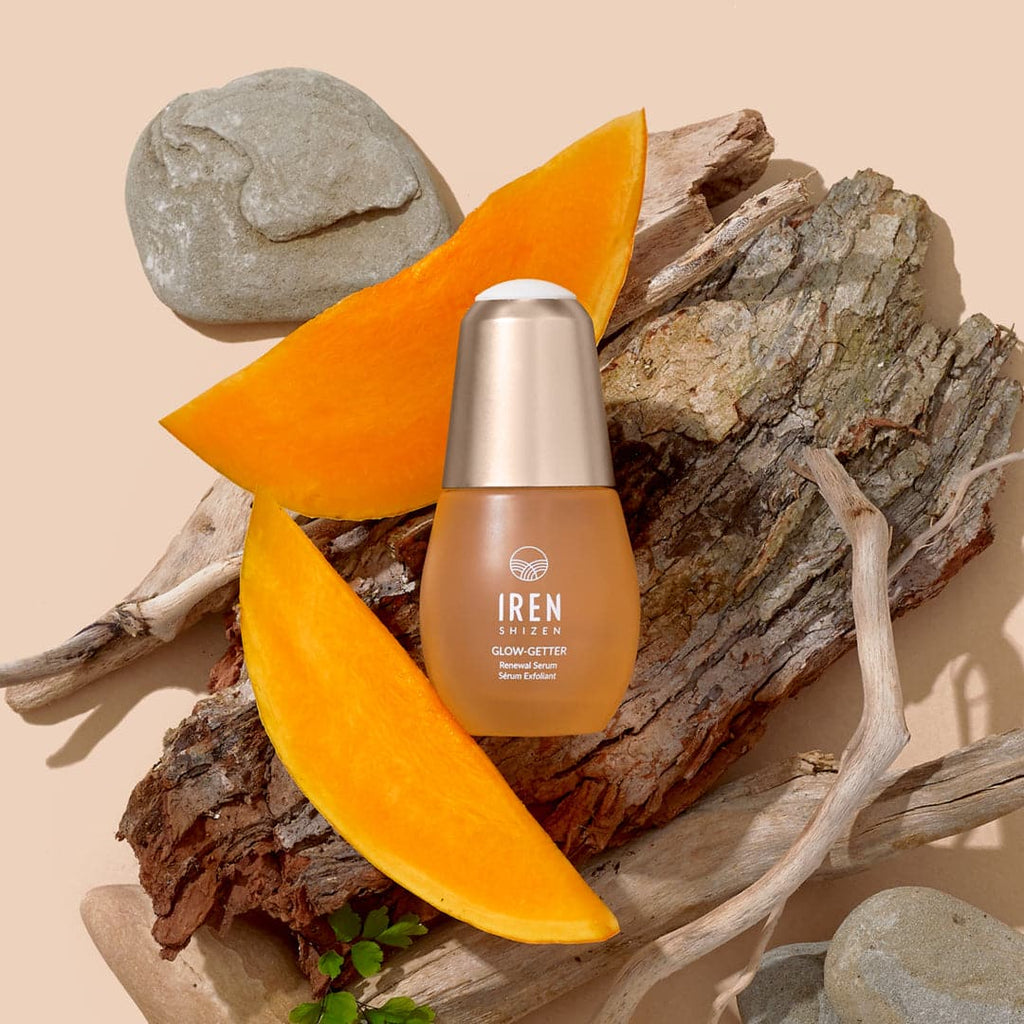 A bottle of IREN Shizen's custom skincare CLEAR UP Anti-Blemish Set next to a slice of orange.