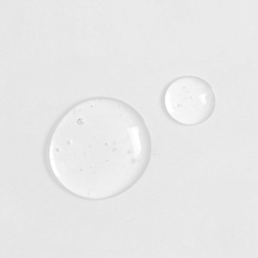 Two Japanese skincare water droplets on a white surface.
