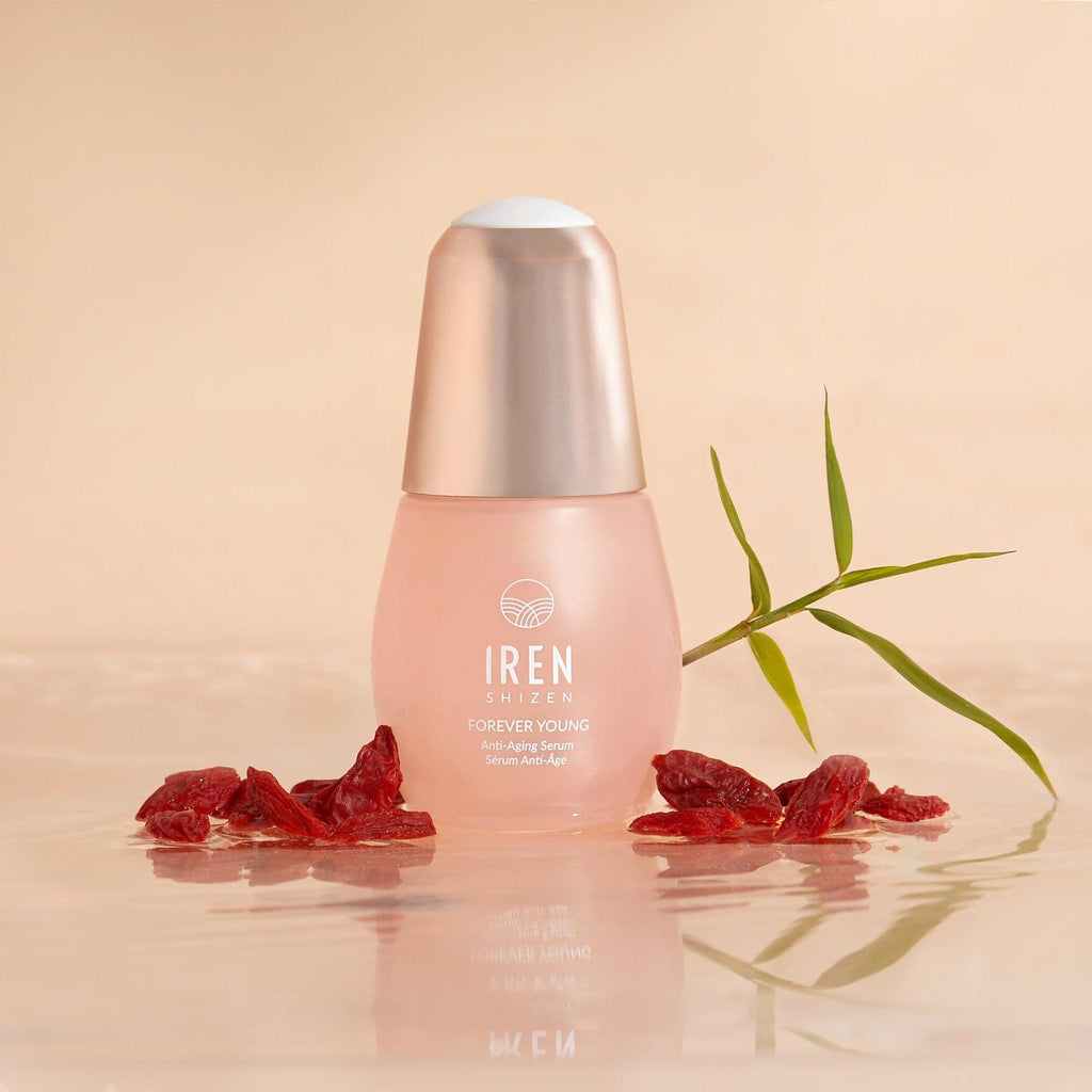 A bottle of customized FOREVER YOUNG Japanese skincare serum by IREN Shizen with red berries on top of it.