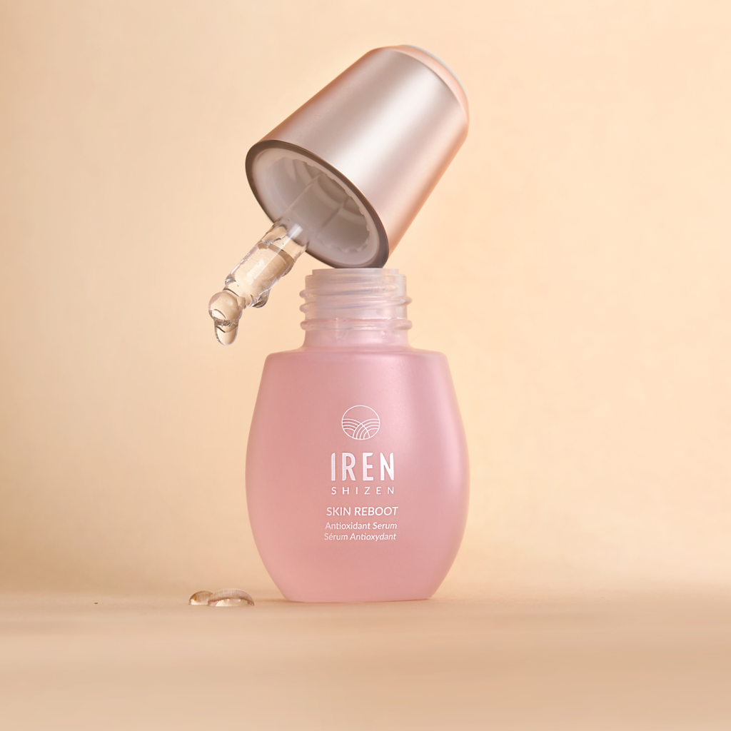 A bottle of IREN Shizen customized skincare, GLOW UP PRO Skin Genie Pro + Anti-Aging Set, with a pink liquid on top of it.